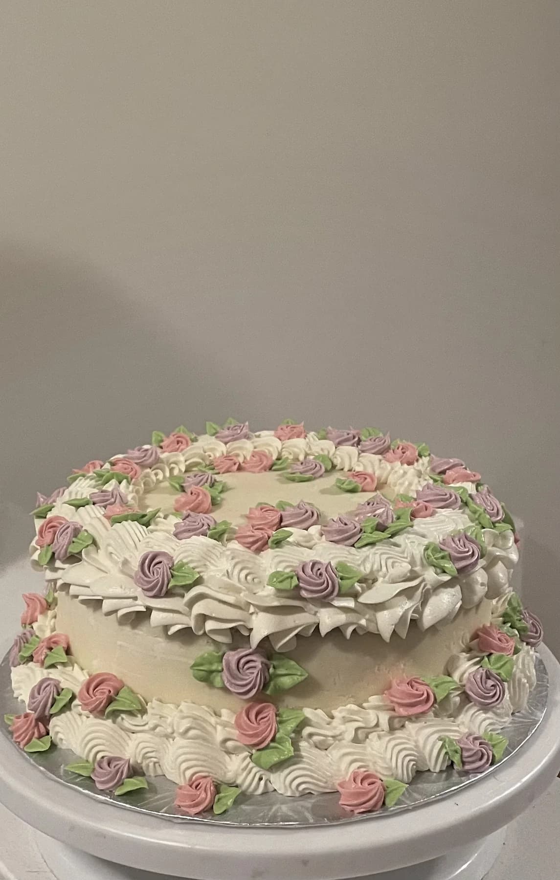 White vintage cake covered in hand-piped pink and green flowers