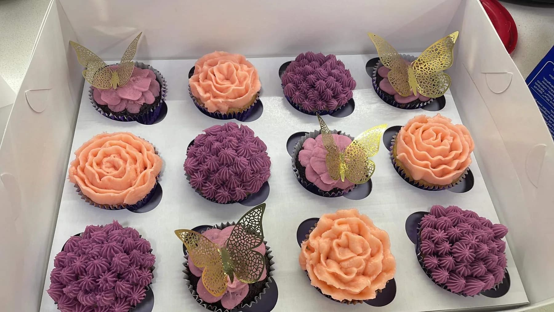 Purple and peach floral cupcakes decorated with butterfly toppers