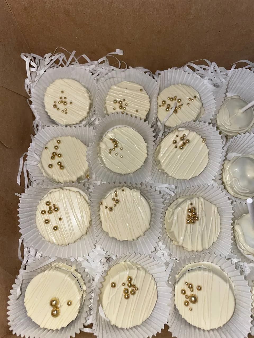 White chocolate covered Oreos with gold pearls boxed with cake pops