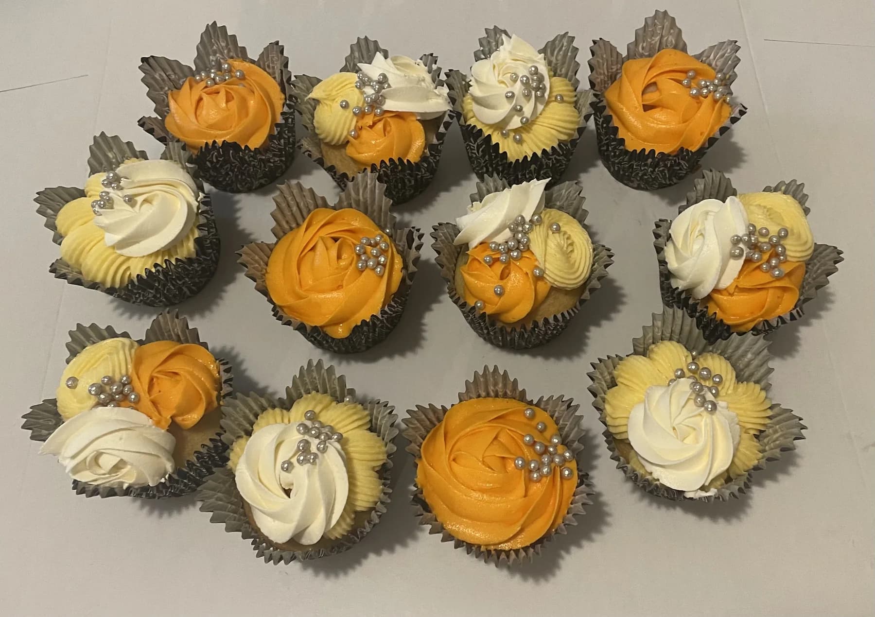 Orange, white, and gold cupcakes with varied buttercream piping