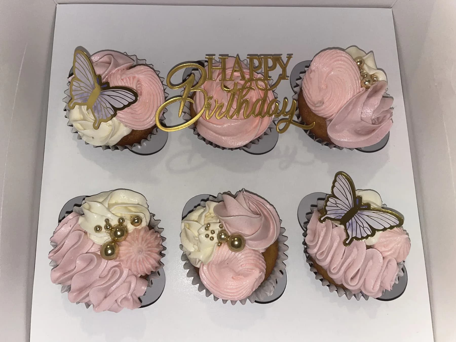 Pink birthday cupcakes with butterflies and a gold topper